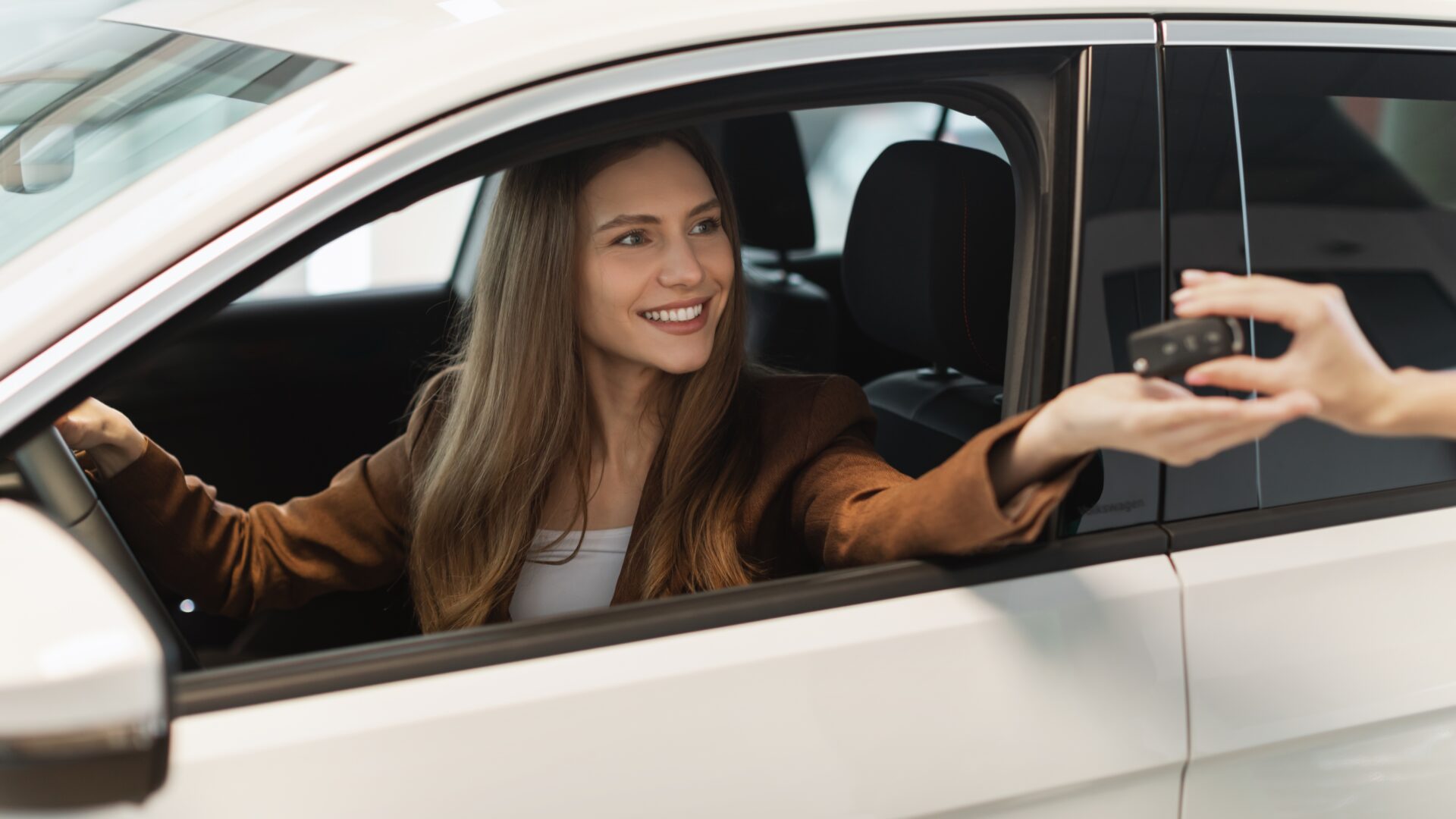 Mujer en coche nuevo que acepta las llaves del vendedor